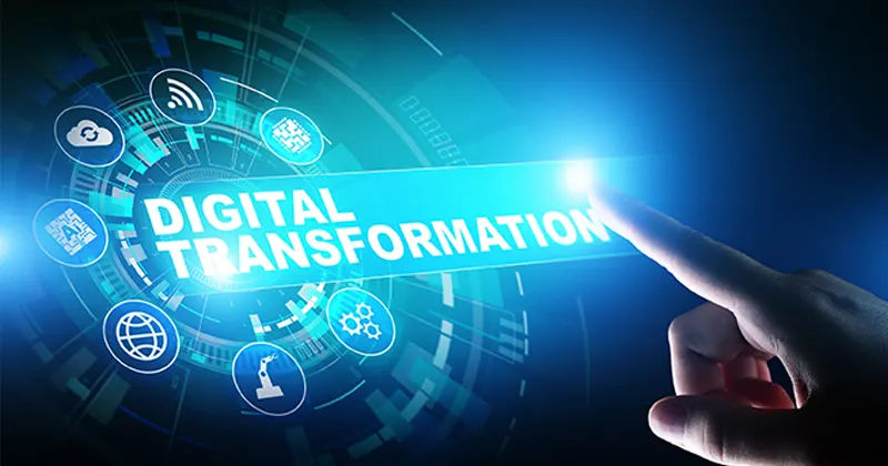 Sur un écran vertical, des symboles représentants des technologies forment un cercle, au centre duquel il y a le texte "digital transformation". Une main montre du doigt ce texte sur l’écran.