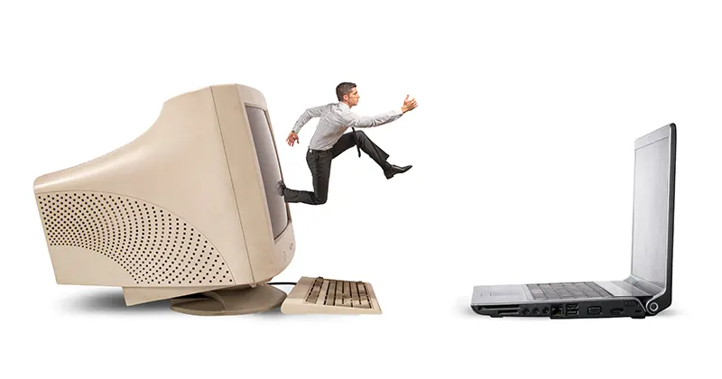 Hombre salta desde un ordenador antiguo a un moderno portatil