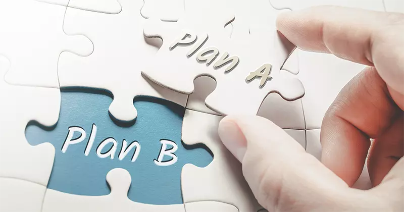 a hand holding a puzzle piece with "plan A" and "plan B" written on the puzzle